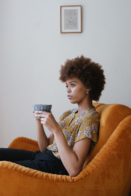 Woman sitting on couch holding coffee cup.